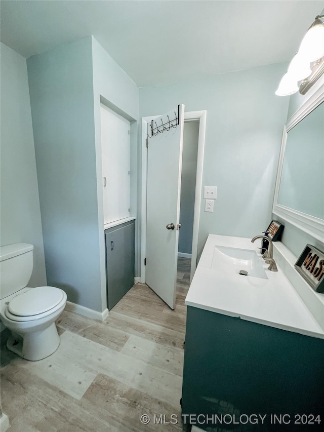 bathroom featuring wood-type flooring, vanity, and toilet