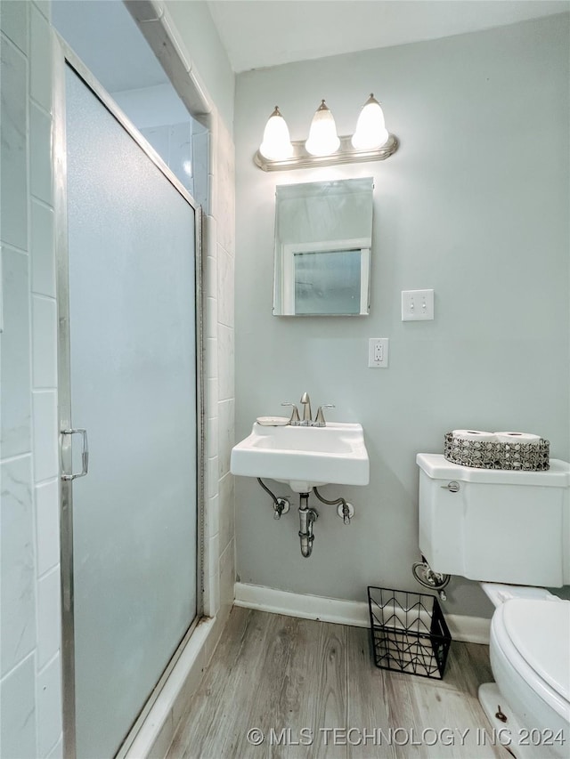 bathroom featuring toilet, wood-type flooring, and a shower with door