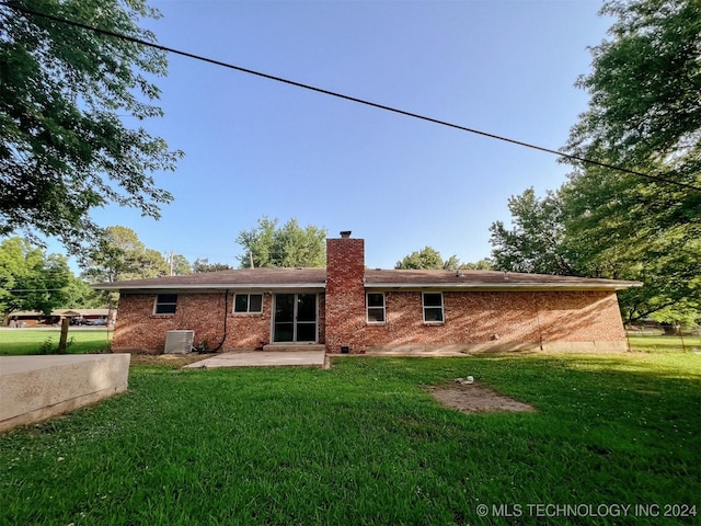 back of property with central AC, a patio area, and a yard