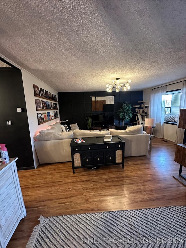 living room featuring a chandelier, wood-type flooring, a textured ceiling, and built in shelves