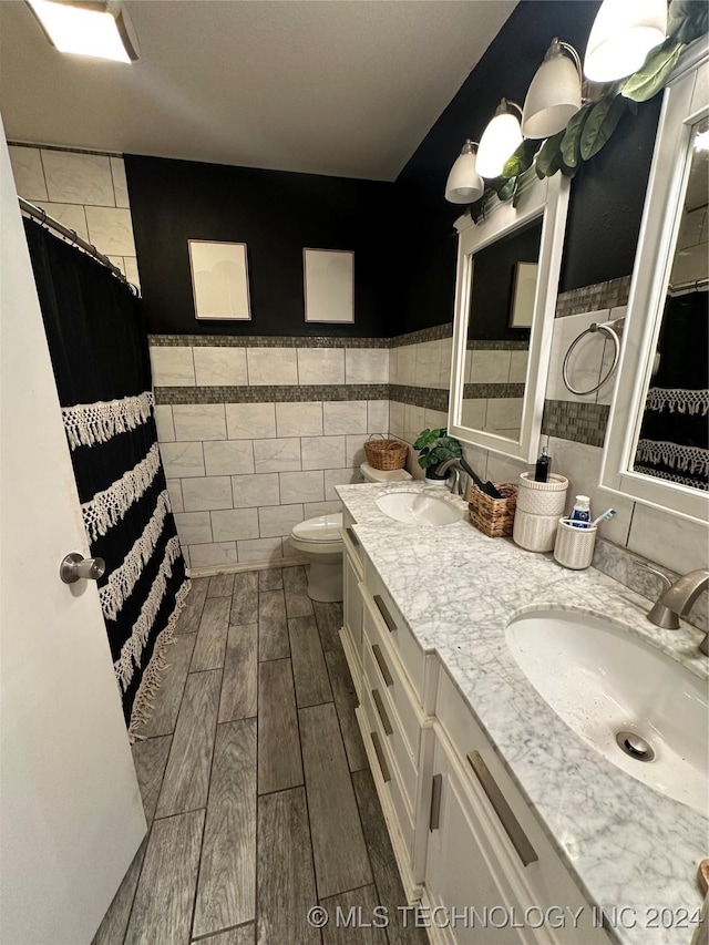 bathroom featuring vanity, tile walls, and toilet