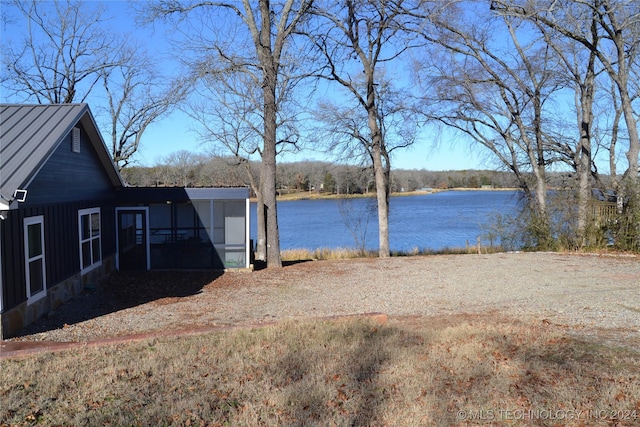 view of yard featuring a sunroom and a water view