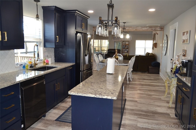 kitchen with sink, black dishwasher, tasteful backsplash, stainless steel refrigerator with ice dispenser, and a kitchen island