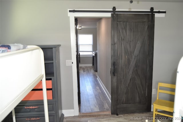 bedroom featuring dark hardwood / wood-style flooring and a barn door