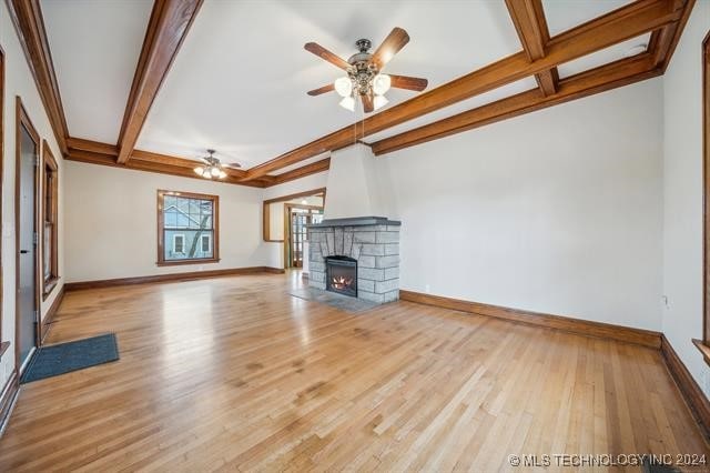 unfurnished living room with beam ceiling, light hardwood / wood-style floors, a fireplace, and ceiling fan