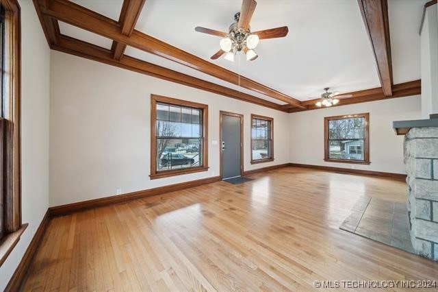 unfurnished living room featuring beam ceiling, ceiling fan, a fireplace, and light hardwood / wood-style flooring