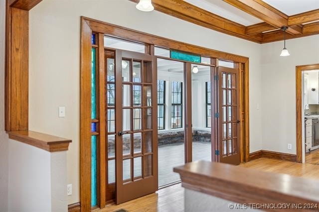 doorway with french doors, beamed ceiling, light hardwood / wood-style floors, and coffered ceiling