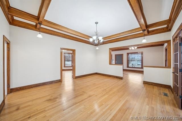 unfurnished living room featuring beamed ceiling, a chandelier, and coffered ceiling