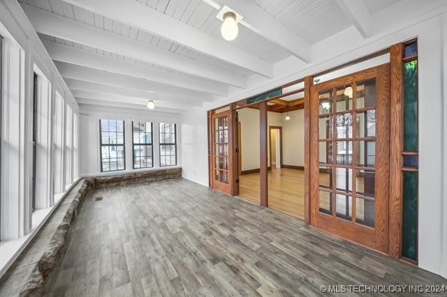 unfurnished sunroom featuring beamed ceiling and french doors