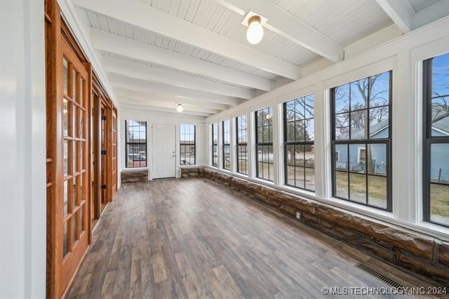 unfurnished sunroom featuring beamed ceiling