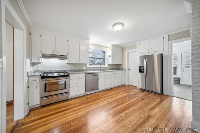 kitchen with white cabinets, sink, light wood-type flooring, ornamental molding, and appliances with stainless steel finishes