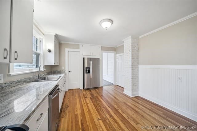 kitchen with white cabinets, sink, light stone countertops, and stainless steel appliances