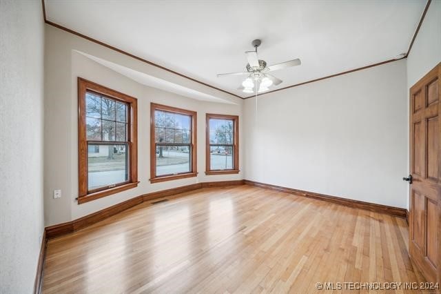 empty room with a wealth of natural light, light hardwood / wood-style flooring, ceiling fan, and crown molding