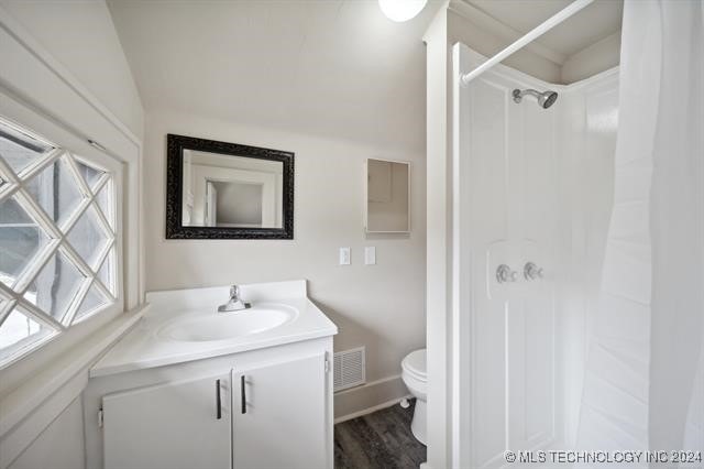 bathroom with a shower, vanity, hardwood / wood-style flooring, and toilet