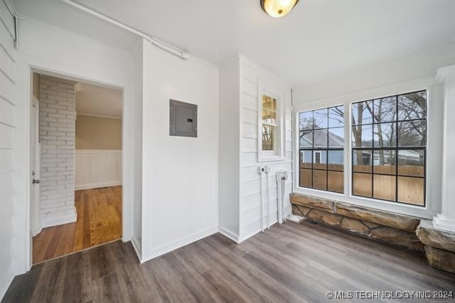 interior space with dark hardwood / wood-style flooring, electric panel, and crown molding