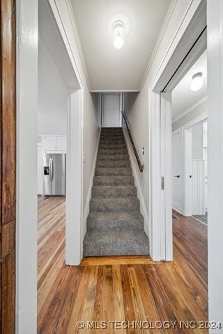 stairs featuring hardwood / wood-style flooring and ornamental molding