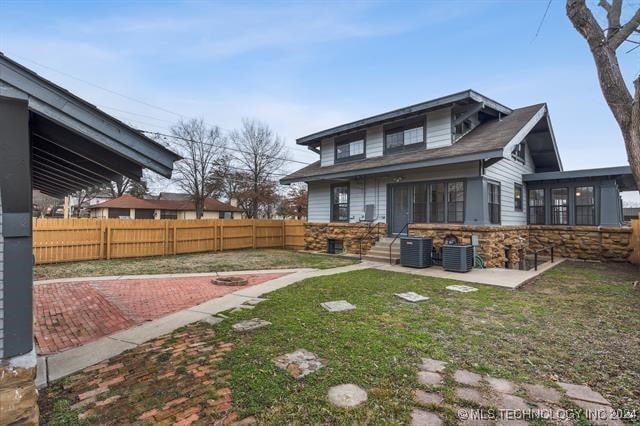 rear view of house with central AC unit, a yard, and a patio