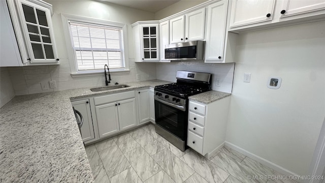 kitchen featuring appliances with stainless steel finishes, light stone counters, white cabinetry, and sink