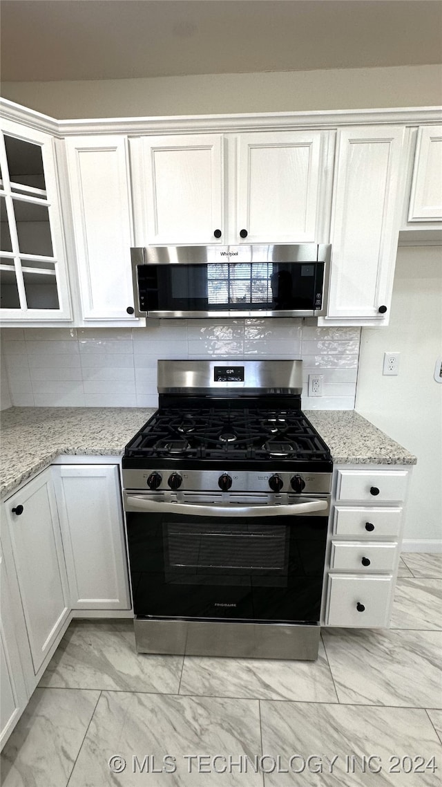 kitchen featuring light stone countertops, white cabinetry, tasteful backsplash, and stainless steel appliances