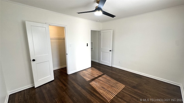 unfurnished bedroom featuring ceiling fan, dark hardwood / wood-style floors, a spacious closet, ornamental molding, and a closet