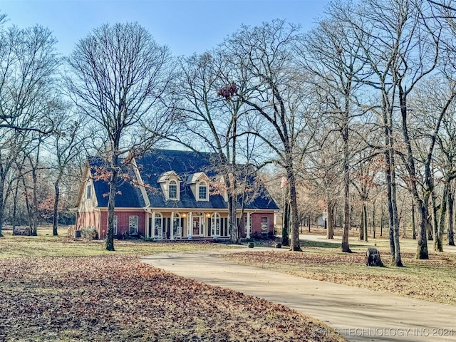 cape cod home with covered porch and a front yard