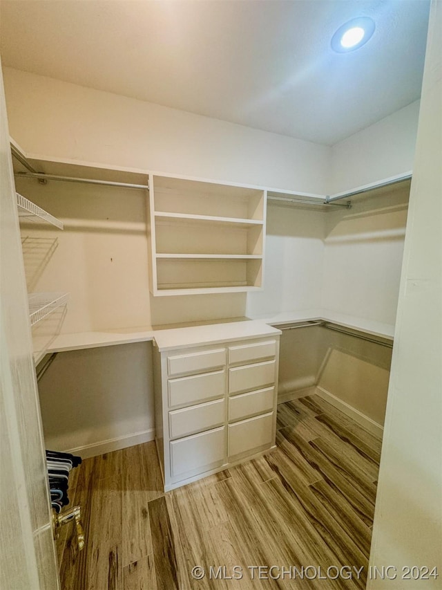 walk in closet with light hardwood / wood-style floors