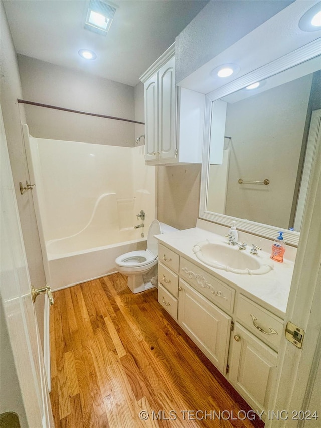 full bathroom with hardwood / wood-style floors, vanity,  shower combination, and toilet