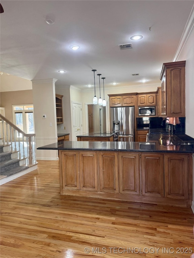 kitchen with sink, light hardwood / wood-style flooring, decorative light fixtures, kitchen peninsula, and stainless steel appliances