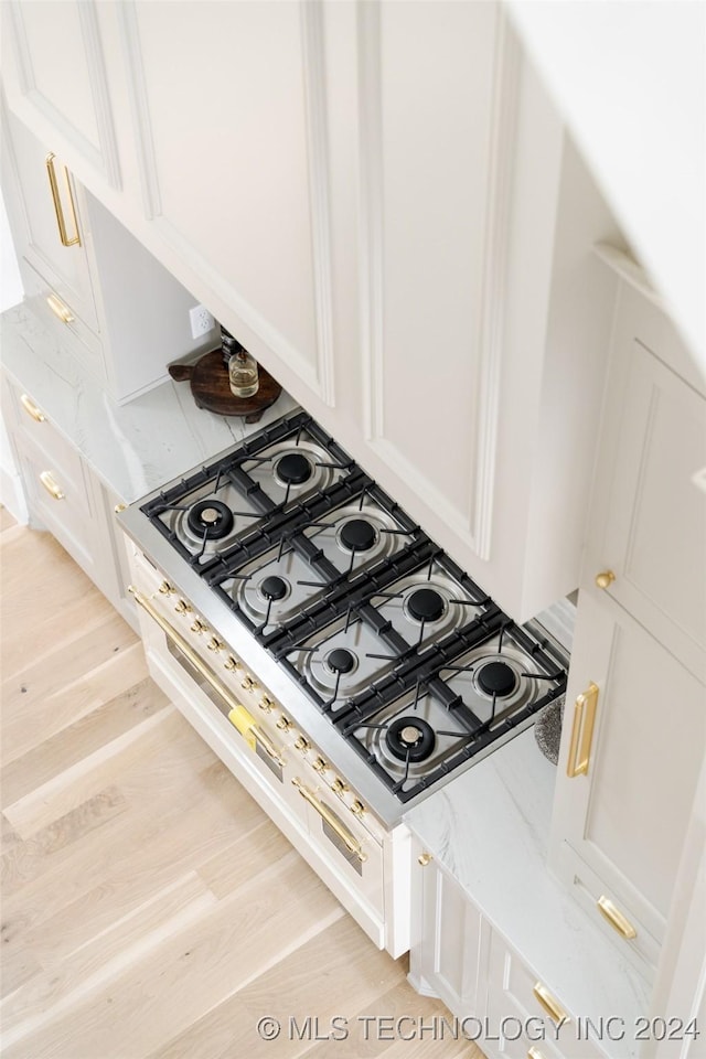 interior details featuring white cabinetry, stovetop, and light hardwood / wood-style flooring