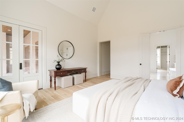 bedroom with light wood-type flooring and high vaulted ceiling