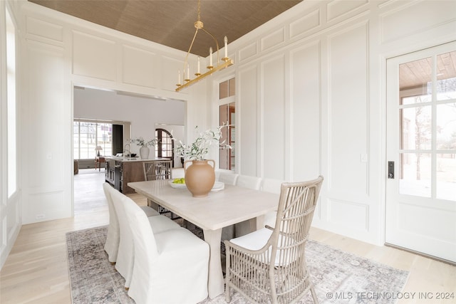 dining area featuring a notable chandelier, light hardwood / wood-style floors, and wood ceiling