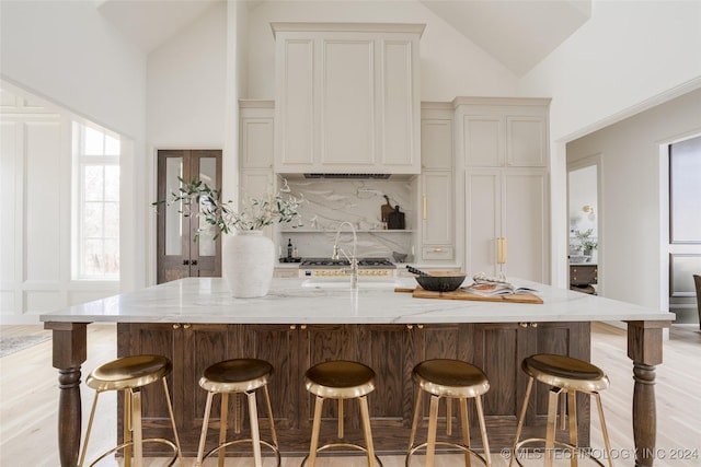 kitchen featuring a large island, sink, light stone countertops, backsplash, and a kitchen bar