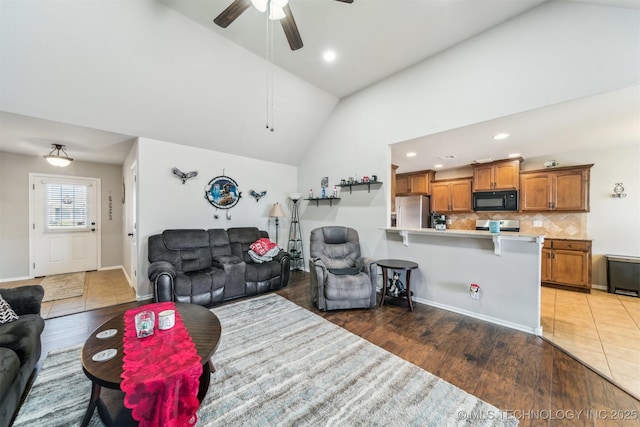 living room featuring ceiling fan, dark wood-type flooring, and high vaulted ceiling