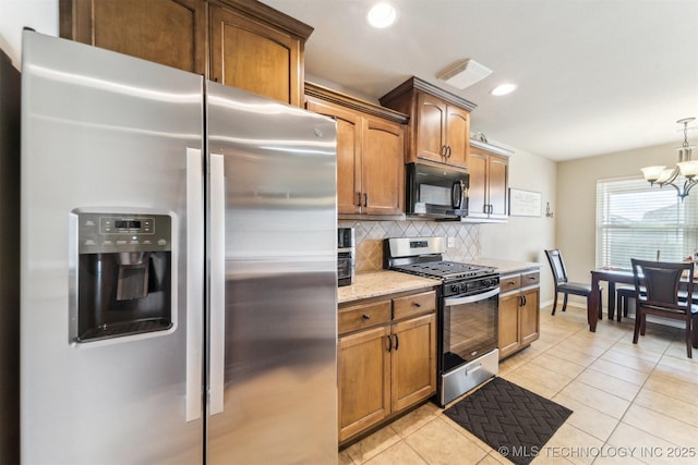 kitchen featuring a chandelier, light tile patterned floors, appliances with stainless steel finishes, and tasteful backsplash