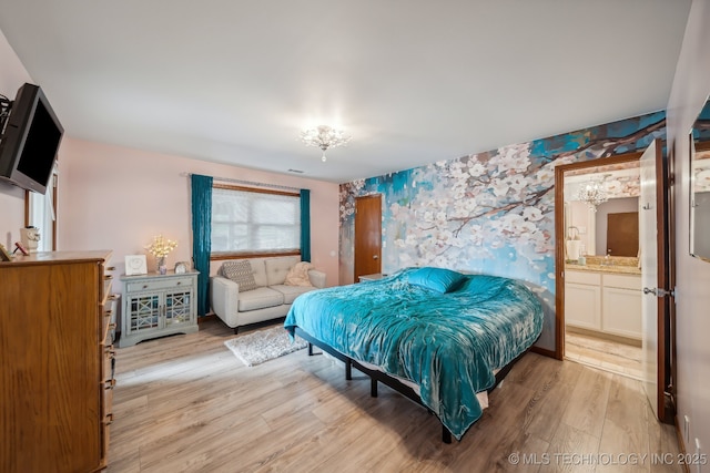 bedroom featuring a chandelier, light hardwood / wood-style flooring, and ensuite bath