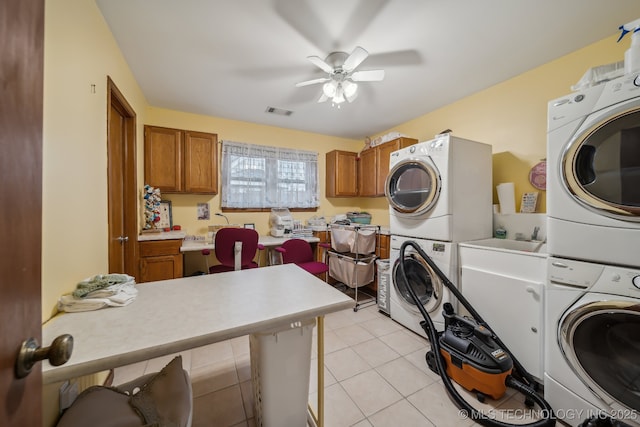 clothes washing area with light tile patterned floors, stacked washing maching and dryer, and ceiling fan