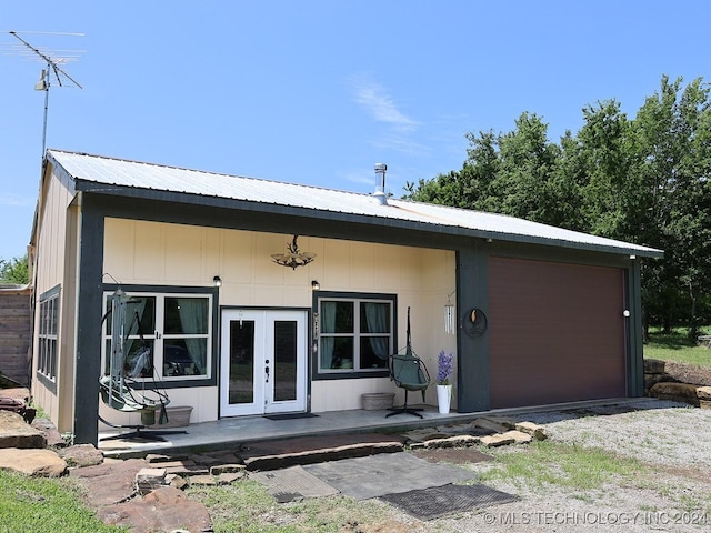 back of property featuring french doors, a garage, and metal roof