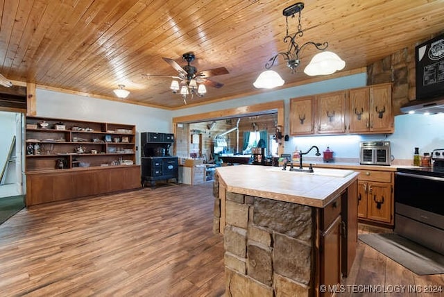 kitchen with sink, wood-type flooring, decorative light fixtures, stainless steel electric stove, and a kitchen island with sink