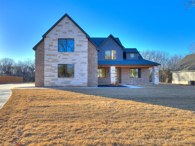 view of front of property with a front lawn, brick siding, stone siding, and roof with shingles