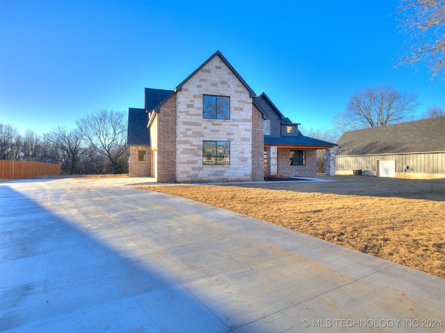 view of front facade featuring stone siding, roof with shingles, and a front lawn