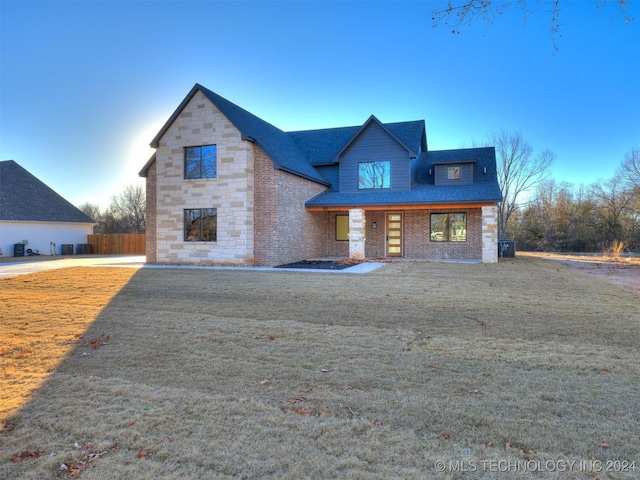 view of front of home with stone siding, brick siding, roof with shingles, and a front yard