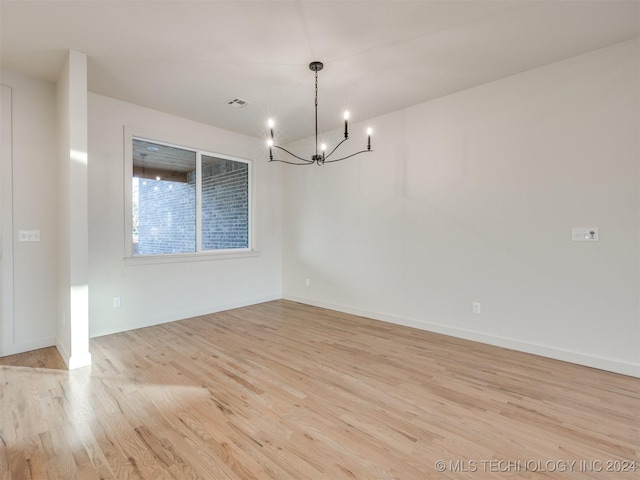 unfurnished dining area featuring an inviting chandelier and light hardwood / wood-style flooring