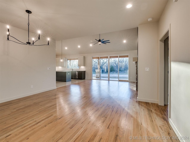 unfurnished living room with ceiling fan with notable chandelier, light hardwood / wood-style flooring, and sink