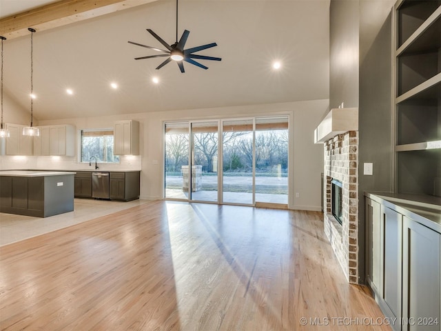 unfurnished living room with sink, a brick fireplace, ceiling fan, light hardwood / wood-style floors, and beam ceiling