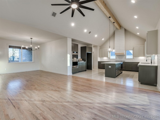 unfurnished living room featuring beamed ceiling, ceiling fan with notable chandelier, light hardwood / wood-style floors, and high vaulted ceiling