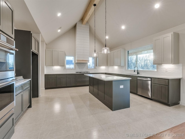 kitchen with beam ceiling, gray cabinetry, a center island, and appliances with stainless steel finishes