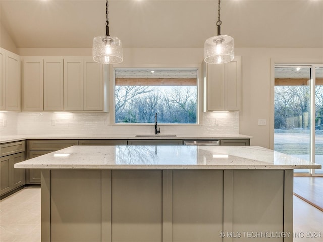 kitchen featuring light stone countertops, gray cabinetry, sink, a center island, and hanging light fixtures