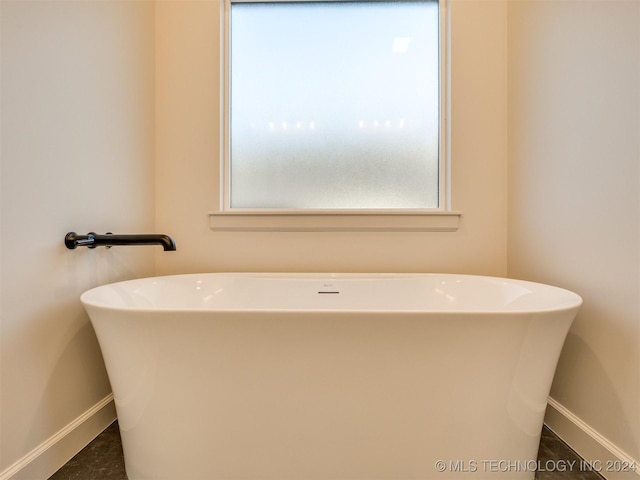 full bath with a freestanding bath and baseboards