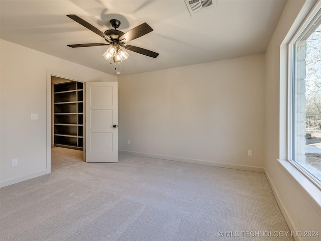 empty room with ceiling fan, a healthy amount of sunlight, and light carpet