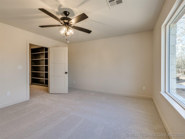 spare room with baseboards, visible vents, a wealth of natural light, and light carpet